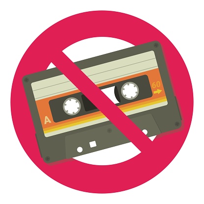 Audio cassette crossed out by the circular red prohibition symbol in flat design style