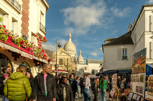 Paris, France - February 17, 2024 : View of crowds of tourists at the busy and picturesque Montmartre area, famous for artists and restaurants and the Sacred heart church in Paris France