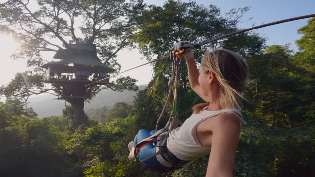 Young woman zip lining in the jungle of Laos