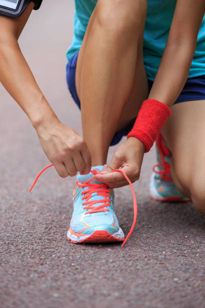 istock Young woman runner tying shoelaces 2116949901
