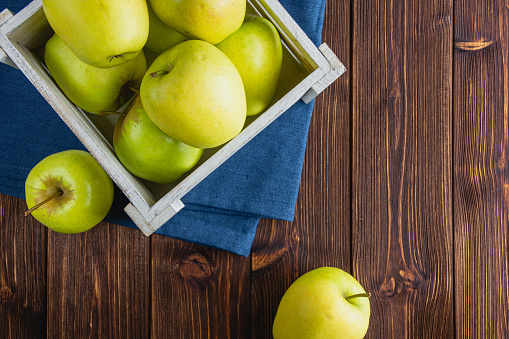 Yellow apples in a crate on a wooden background. Top view of fresh fruits. Copy space.