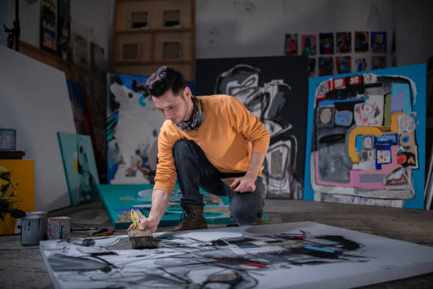 Mid adult artist, dedicated primarily in abstract art is painting his new piece.