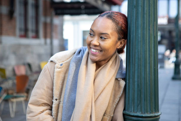 istock Smiling woman standing by a lamp post on the pavement 2116973318