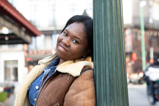istock Smiling woman standing by a lamp post on the pavement 2116981194