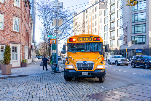 Wall Street, Manhattan, New York, USA - March, 2024.  Modern New York yellow school bus in Greenwich Village.
