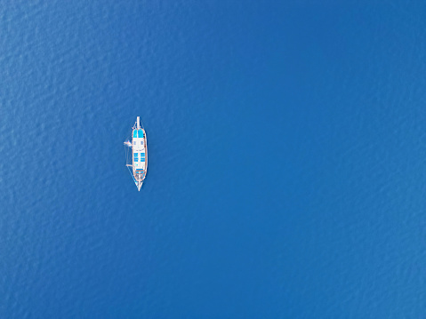 Aerial footage of boat directly from above in blue sea in the morning, in the gulf of Ören in Muğla Province of Turkey, The Blue Waters of Aegean Sea