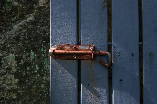 Close-up on a rusty bolt on a wooden gate in the nothing sun.