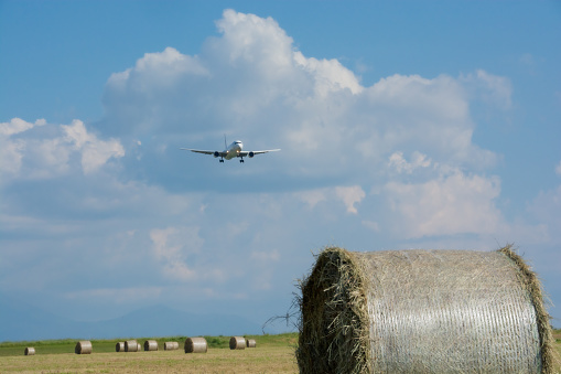 Hay bales and blue sky and jet airliner