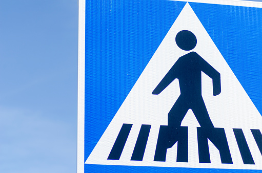 partial view of a crosswalk sign with blue sky in the background