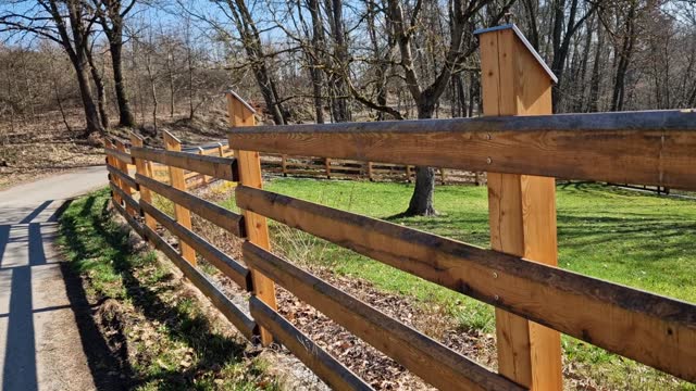 rural farm style wooden fence. the posts from the beam are on metal spikes so they don't rot from the ground. the top is beveled and covered with a sheet metal roof against water ingress
