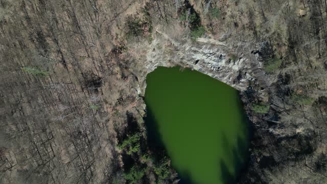 mining in the quarry has long since ended and the quarry is already reclaimed and blends into the forest landscape. circular deep flooded lake. search for the drowned using a police drone