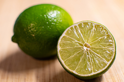 Juicy lime slices flat lay with green leaves on marble background. Top view