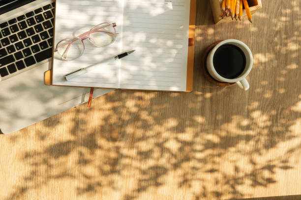 istock Laptop, notepad, glasses and coffee cup on wooden table. Top view with copy space. 2117152948