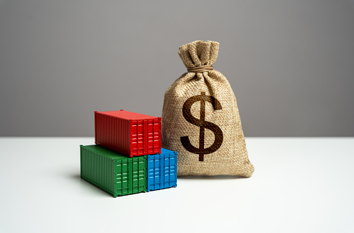 Stack of shipping containers and dollar money bag. Trade, economics and transport industry. GDP and production. Import or export. Tariffs and tax collections. Production of containers.