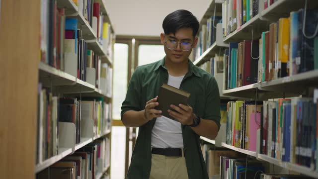 Young man browsing through the shelves in the library to find a book to read