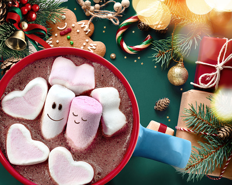 Marshmallows couple in mug with hot chocolate on the table with traditional Christmas decorations top view