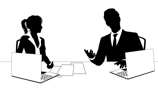 News anchor presenters or business people seated at a desk with laptops in silhouette