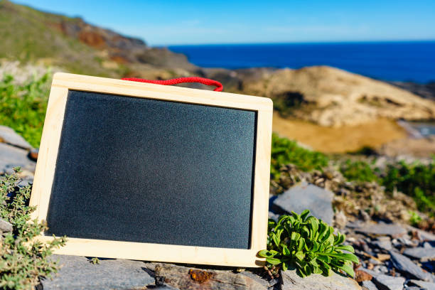Blank black board against sea coast in Spain. Mockup template for text. Travel and holidays.