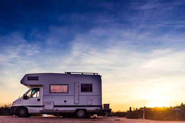 istock Camper car on beach at sunrise 2117215810