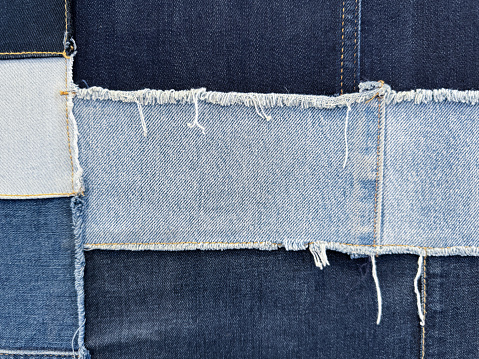 Stock photo showing close-up view of patches of denim, in various colours, stitched together in a swatch to assist customers in the selection of their preferred pair of jeans.