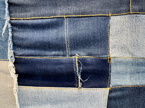 Stock photo showing close-up view of patches of denim, in various colours, stitched together in a swatch to assist customers in the selection of their preferred pair of jeans.