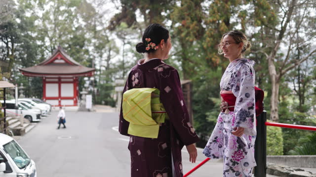 Female friends in kimono talking in shrine