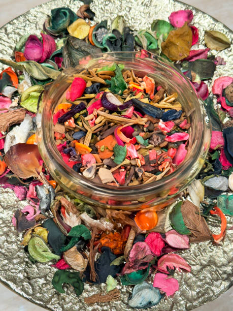 Stock photo showing close-up, elevated view of large plate containing fragrant, natural, plant potpourri made from dried flower petals, wood and cork.