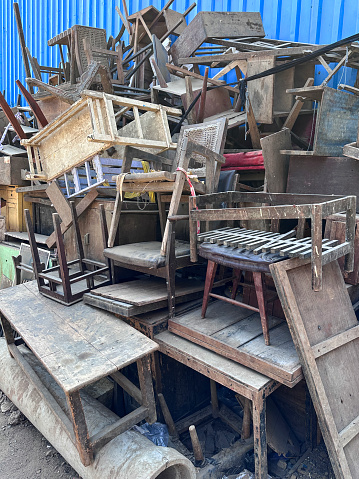 Stock photo showing reclaimed wooden tables and benches stacked high in outdoor area of an antique street market.