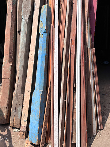 Stock photo showing reclaimed wooden doors and painted stair bannisters lined up in a row in the sunshine of an antique street market.