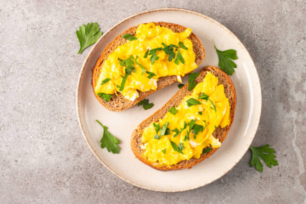 istock Scrambled eggs with green herbs on wheat-rye crispy toast. 2117238875