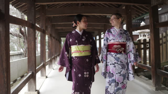 Female friends in kimono walking through the shrine corridor