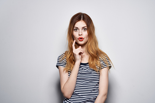 beautiful woman in a striped t-shirt gesture with his hands light background. High quality photo