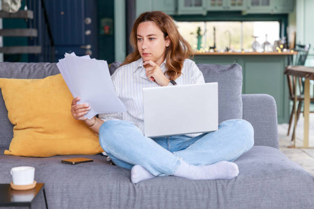 istock Young freelancer woman get over paperwork while working from living room 2117263202