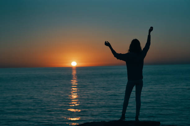 istock woman gesturing with her hands and sunset sea landscape beach 2117264257
