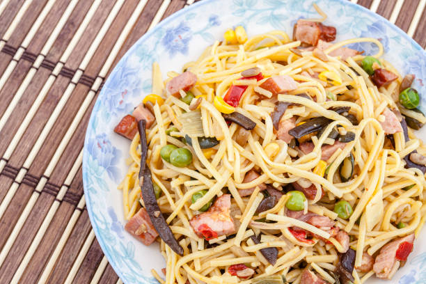 Traditional yellow Chinese noodles with vegetables, meat and mushrooms. Selective focus with shallow depth of field.