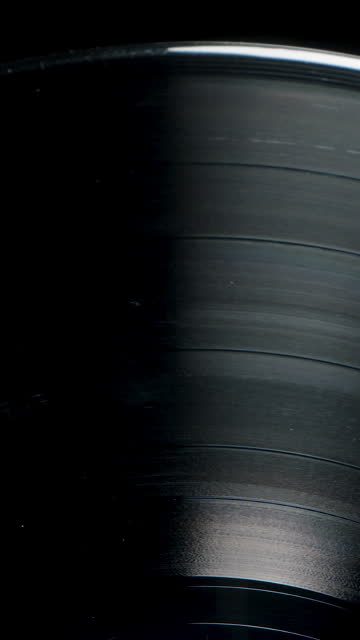 Macro zoom of a rotating vinyl record on a black background. A close-up of the spiral sound track groove.