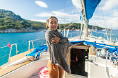 Young woman relaxing in sailboat cockpit after swimming in sea