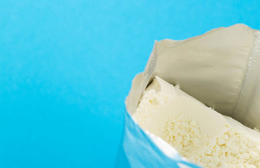 Powdered baby food for preparing milk formula in a shiny bag on a blue background