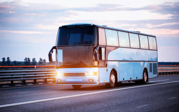 istock A blue comfortable bus carries passengers along the highway in the evening with the headlights on. The concept of travel and tourist tours from travel agencies. 2117365859