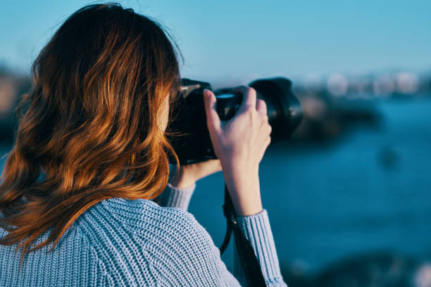 istock woman with camera on nature sea landscape 2117406265