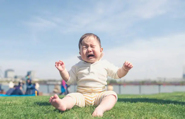 a crying baby sit on the grass