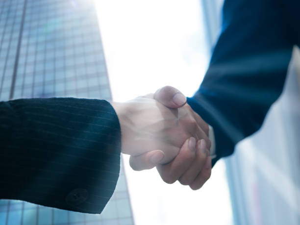 istock Businessmen shaking hands with partners, introducing their own, doing business, merging and acquiring, forming joint ventures, background in finance and investing, working as a team, earning success 2117431427