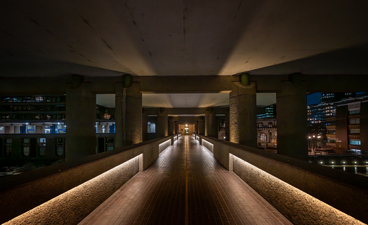 London, UK: Deserted high-level walkway at night on the Barbican Estate in the City of London. The Barbican Estate is a prominent example of Brutalist architecture in London