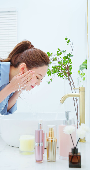side view of closeup asian woman is washing her face happily in bathroom