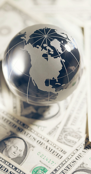 glass miniature globe against the background of American dollar bills