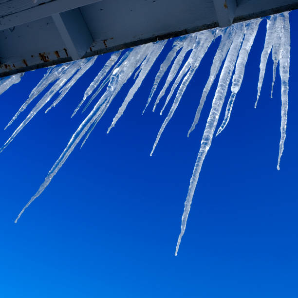 Crystal clear icicles hanging from roof in winter with blue sky