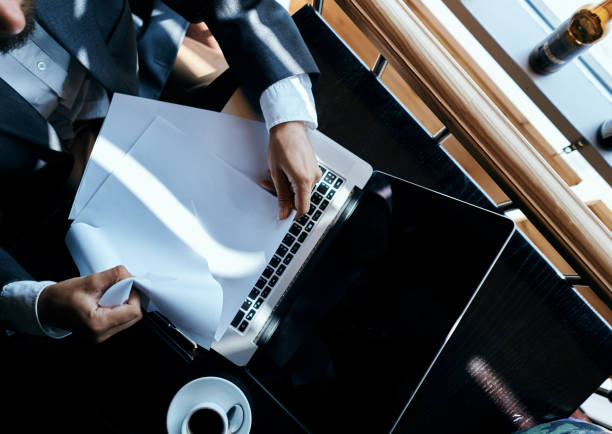 istock Business man sitting in a cafe in front of a laptop documents coffee cup executive top view technology lifestyle 2117475048