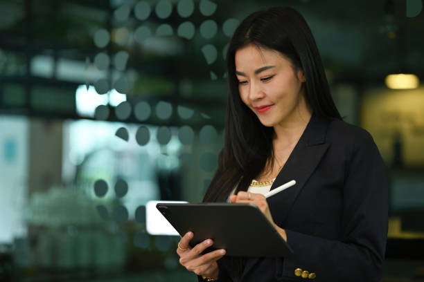 istock Gorgoeus asian female manager standing in modern office and using digital tablet. 2117486863