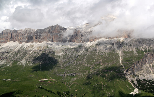 Landscape photo with a view of the mountain massif and the partly cloud-covered peak in the Dolomites