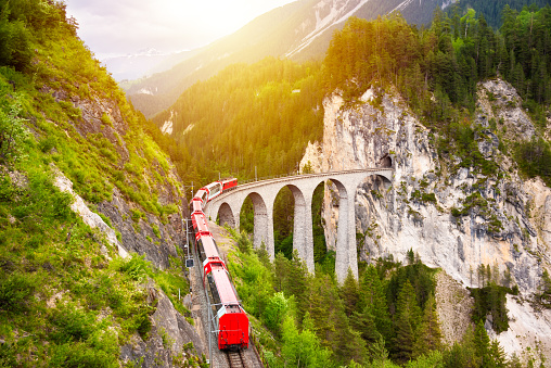 Swiss red train on viaduct in mountain for scenic ride